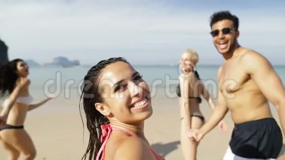 在沙滩上牵着手在水中奔跑的快乐的女孩快乐的男男女女视频的预览图
