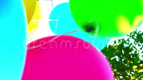 气球生日快乐彩色气球在天空和树叶的背景下缓慢运动视频的预览图