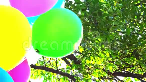 气球生日快乐彩色气球在天空和树叶的背景下缓慢运动视频的预览图
