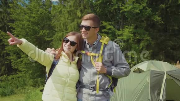 一对浪漫的情侣在远足他们站在帐篷的背景上露营拥抱视频的预览图