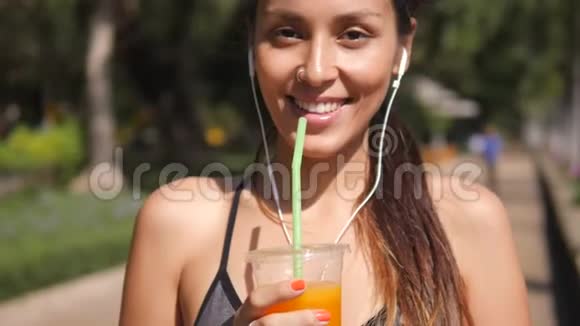 年轻的混合赛跑跑步女孩在城市公园锻炼后喝新鲜橙汁4K慢动作泰国视频的预览图