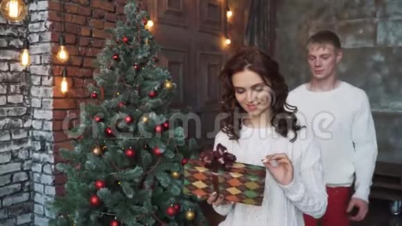 一个穿白毛衣的年轻人给他的女朋友送礼物新年快乐圣诞快乐视频的预览图