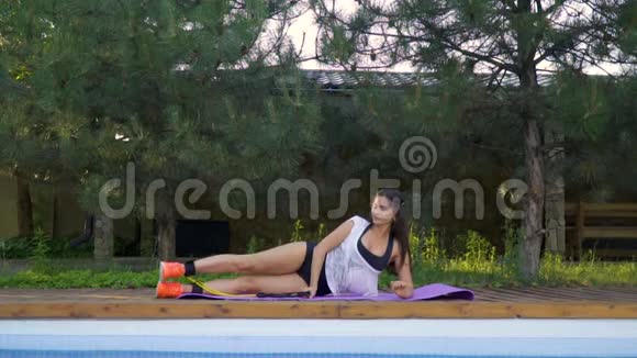 这个深黑肤色的女孩躺在地毯上做瑜伽躺在训练她的腿慢动作视频的预览图