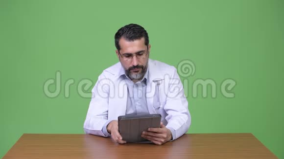 英俊的波斯胡子男医生在使用数码平板电脑时思考视频的预览图