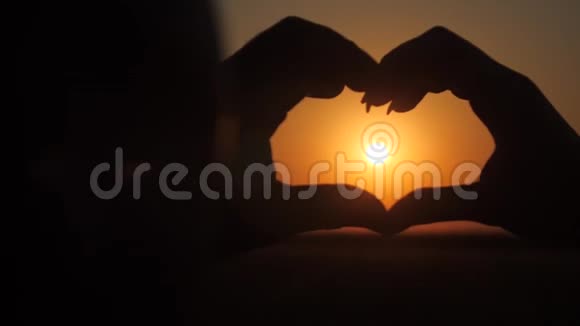 有爱的一对夫妇用自己的双手在红日落下视频的预览图