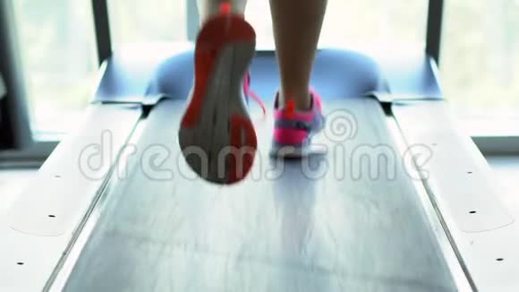 年轻女子在健身房的跑步机上跑步慢动作后视视频的预览图