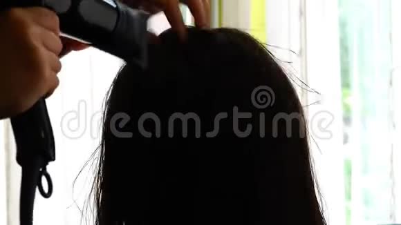 吹风机喷出的暖空气使女孩头发干燥视频的预览图