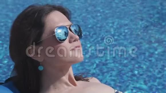 泳池附近的女式日光浴蓝水背景视频的预览图