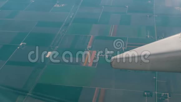 飞机飞过荷兰五彩郁金香美丽的田野从舷窗俯瞰飞机机翼视频的预览图