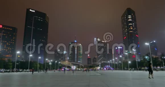 人们在广州的广场上走来走去夜晚大都市色彩鲜艳的高楼大厦视频的预览图