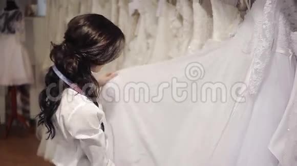 沙龙经理婚礼时尚为新娘挑选一件白色连衣裙视频的预览图