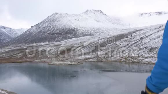 一个带背包的人在山里旅行他的周围是美丽的山脉和清澈的湖泊他拍了照片视频的预览图