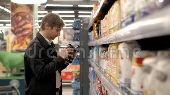 普通的中产阶级在超市里选择罐头食品年轻人在商店杂货店里选择酱油视频的预览图