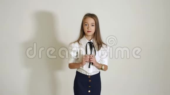 一个年轻可爱的女孩穿着白色的衬衫在工作室的白色背景上摆姿势视频的预览图