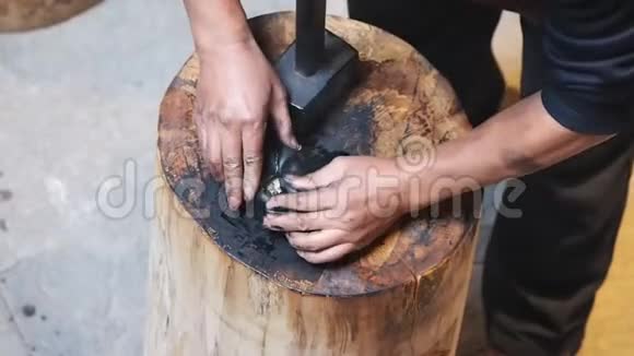 如何制作徽州墨棒系列第四步手工艺人在木砧上用大锤敲打烫手的生墨棒视频的预览图