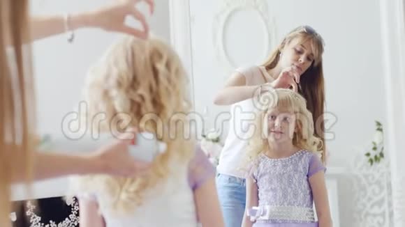 对6岁的女孩来说穿着一件优雅的裙子妈妈做了一个漂亮的发型视频的预览图