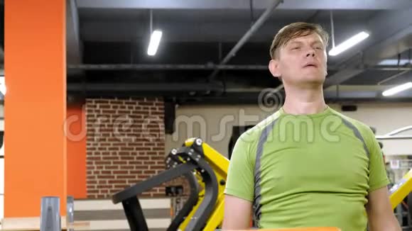 一个男人在后三角洲做运动哑铃坐在健身室里直握手视频的预览图