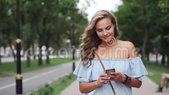 女性在智能手机上输入信息在林荫大道上视频的预览图