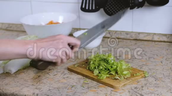 厨房餐桌上的砧板上女性手切生菜的特写敲刀慢动作视频的预览图