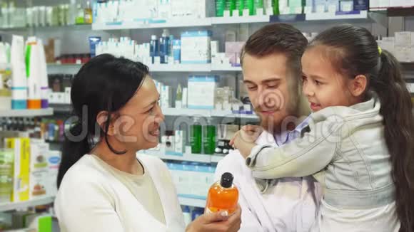 有一个女孩抱在怀里的药剂师和她的母亲在药房里选择了一种药物视频的预览图