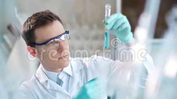 年轻的科学家在实验室检查试管男子戴防护护目镜视频的预览图