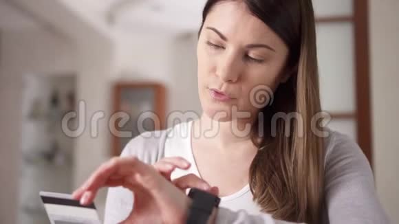 坐在客厅沙发上用智能手表上的信用卡在线购物的女人网上购物视频的预览图