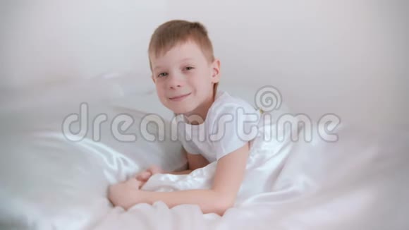 七岁的男孩刚刚醒来躺在床上笑视频的预览图