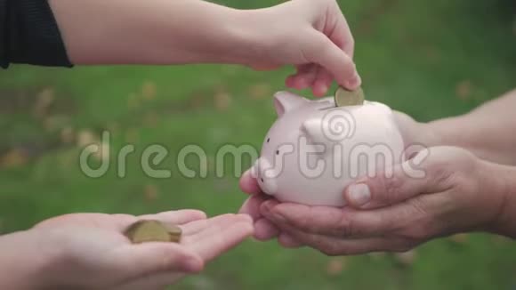 母女俩把硬币放进储蓄罐里女人拿着储蓄罐女孩把硬币放在户外视频的预览图