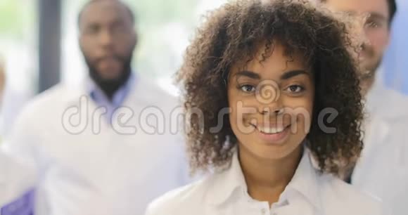 年轻的非裔美国科学家女孩与研究团队在现代实验室快乐微笑不同的男人和女人视频的预览图