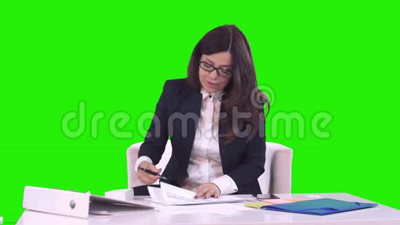 商业女性的肖像布鲁内特戴着眼镜坐在办公室里签着文件微笑着把它们交给了视频的预览图