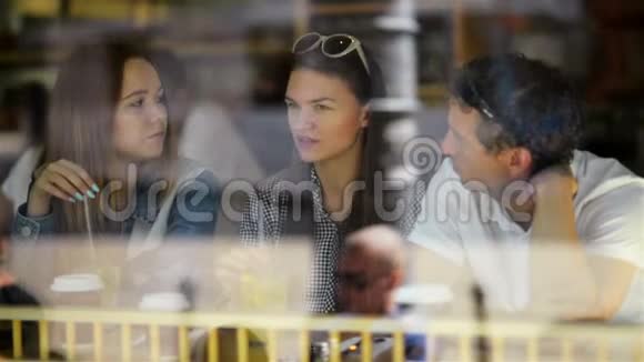 布鲁内特女人和两个朋友坐在咖啡馆喝一些饮料和说话三个朋友都在视频的预览图