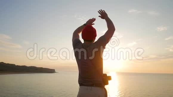 年轻的摄影师游客站在悬崖上挥舞着手臂面对金色的日落高清慢速运动克里米亚俄罗斯视频的预览图