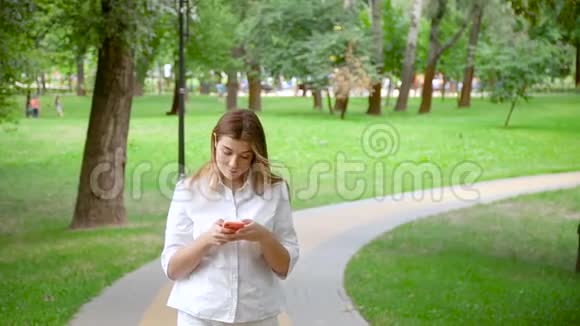 女孩在夏季公园使用智能手机视频的预览图