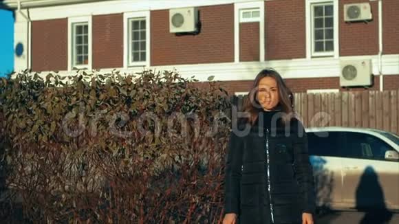 穿着黑色衣服的年轻美女拿着一串钥匙对着棕色的房子视频的预览图
