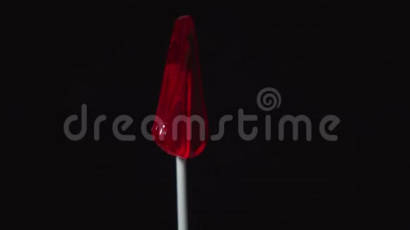 塑料棒上的棒棒糖旋转作为黑色背景上三角形的形式视频的预览图