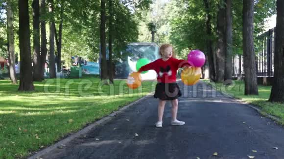 穿裙子的快乐小女孩带着明亮的气球旋转视频的预览图