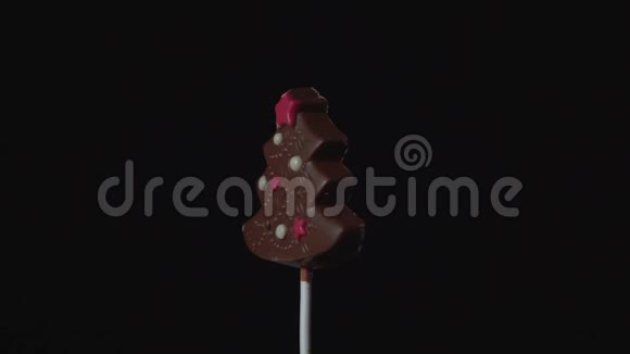 巧克力糖果在黑色背景上以塑料棒旋转作为圣诞树的形式视频的预览图