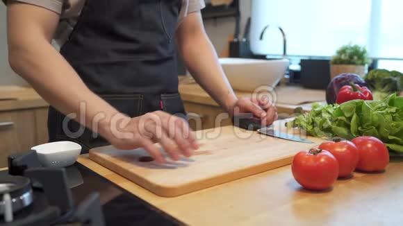 亚洲人手在砧板上切番茄厨房柜台上的新鲜蔬菜特写镜头男的正在准备食物视频的预览图