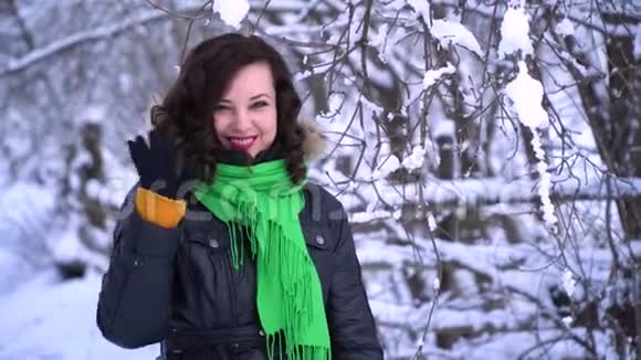 冬天森林里的年轻漂亮女孩看着相机笑着她把他的手挥向照相机视频的预览图