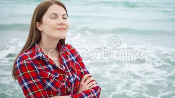 女人看着海滩上的海浪女旅行者在暴风雨天气的海滩度假时很冷视频的预览图