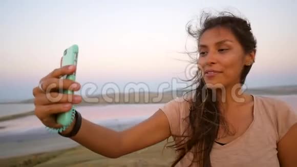 在克里米亚的咸湖年轻的混血女孩用手机与朋友进行视频聊天景色令人惊叹视频的预览图