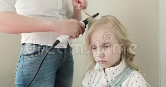 一位年轻的母亲把她悲伤女儿的头发卷起来视频的预览图
