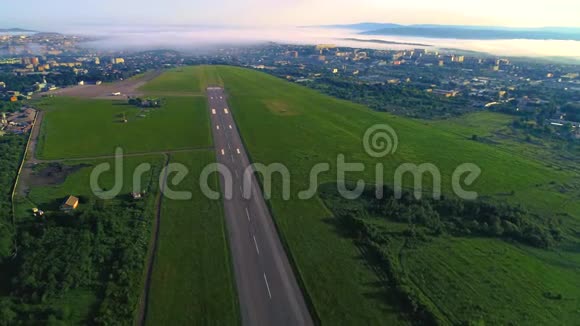 4K射击无人机到跑道两边的绿色田野晨雾笼罩城市视频的预览图