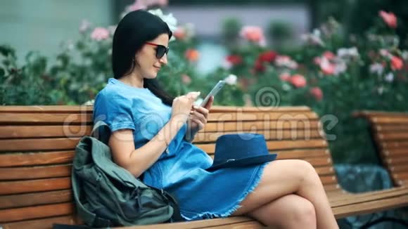 带着手机的女游客在温暖的春天坐在公园里视频的预览图