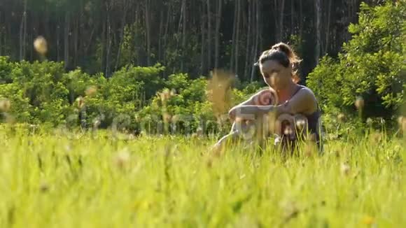幸福的微笑女人在夕阳下的风景田野上的青草上啜泣视频的预览图