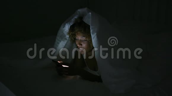 在黑暗的房间里用电话的年轻女子视频的预览图