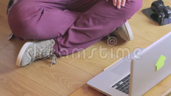 一个男人坐在一台手提电脑旁边拿着相机的特写镜头视频的预览图