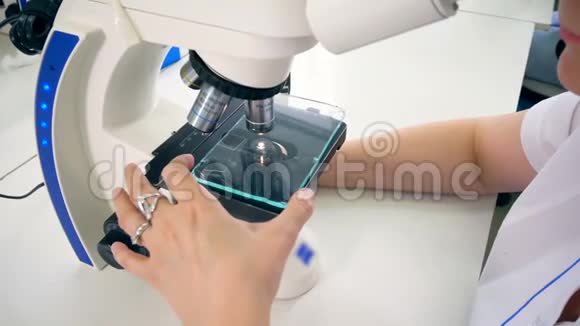 一位女科学家在显微镜下观察某物的俯视图视频的预览图