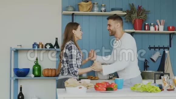 在家厨房做饭的时候快乐的年轻夫妇在厨房里尽情跳舞视频的预览图