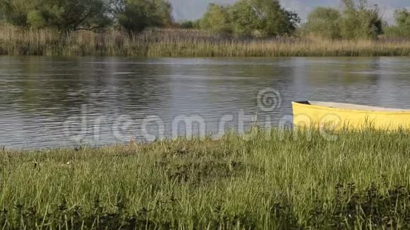平静的河流和一艘黄色的渔船在草地上视频的预览图